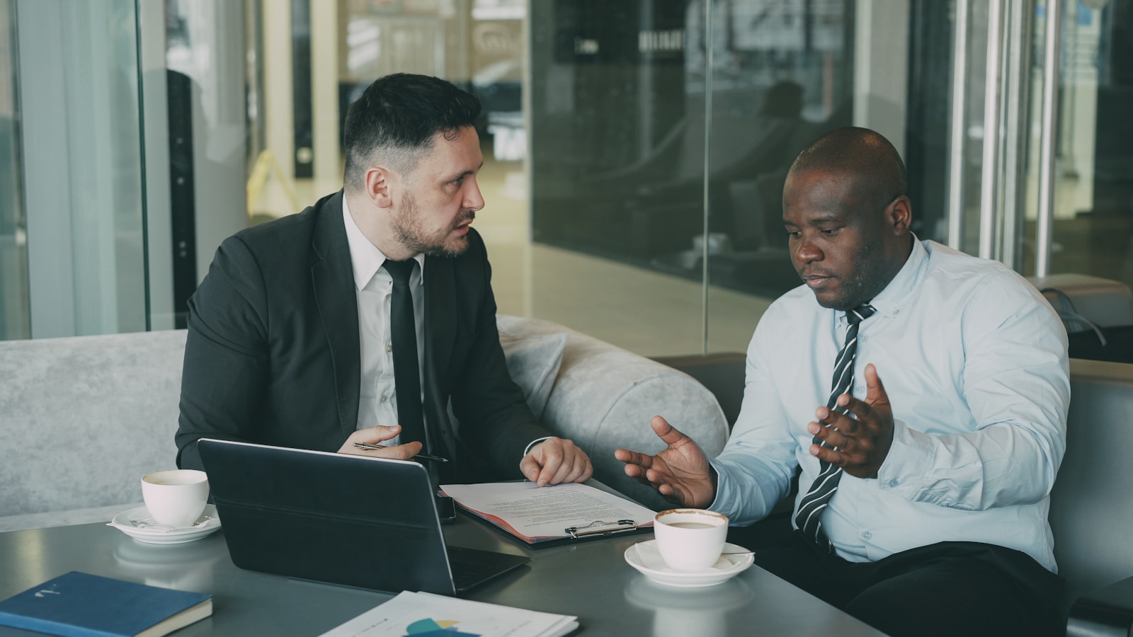 Two businessmen discussing documents at a table.