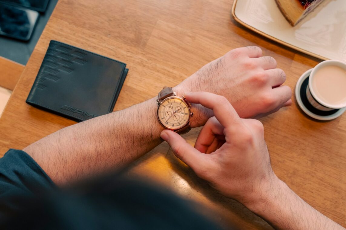 Person checking wristwatch on wooden table